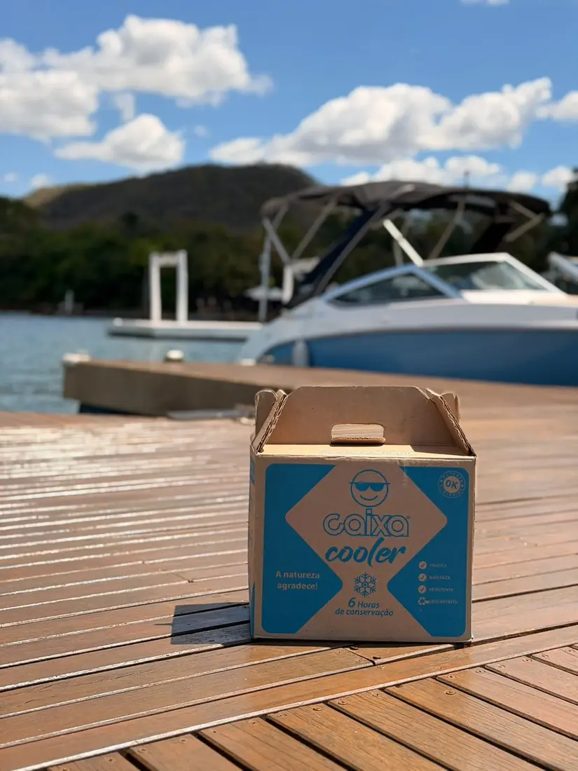 Caixa Cooler no píer com uma lancha ao fundo